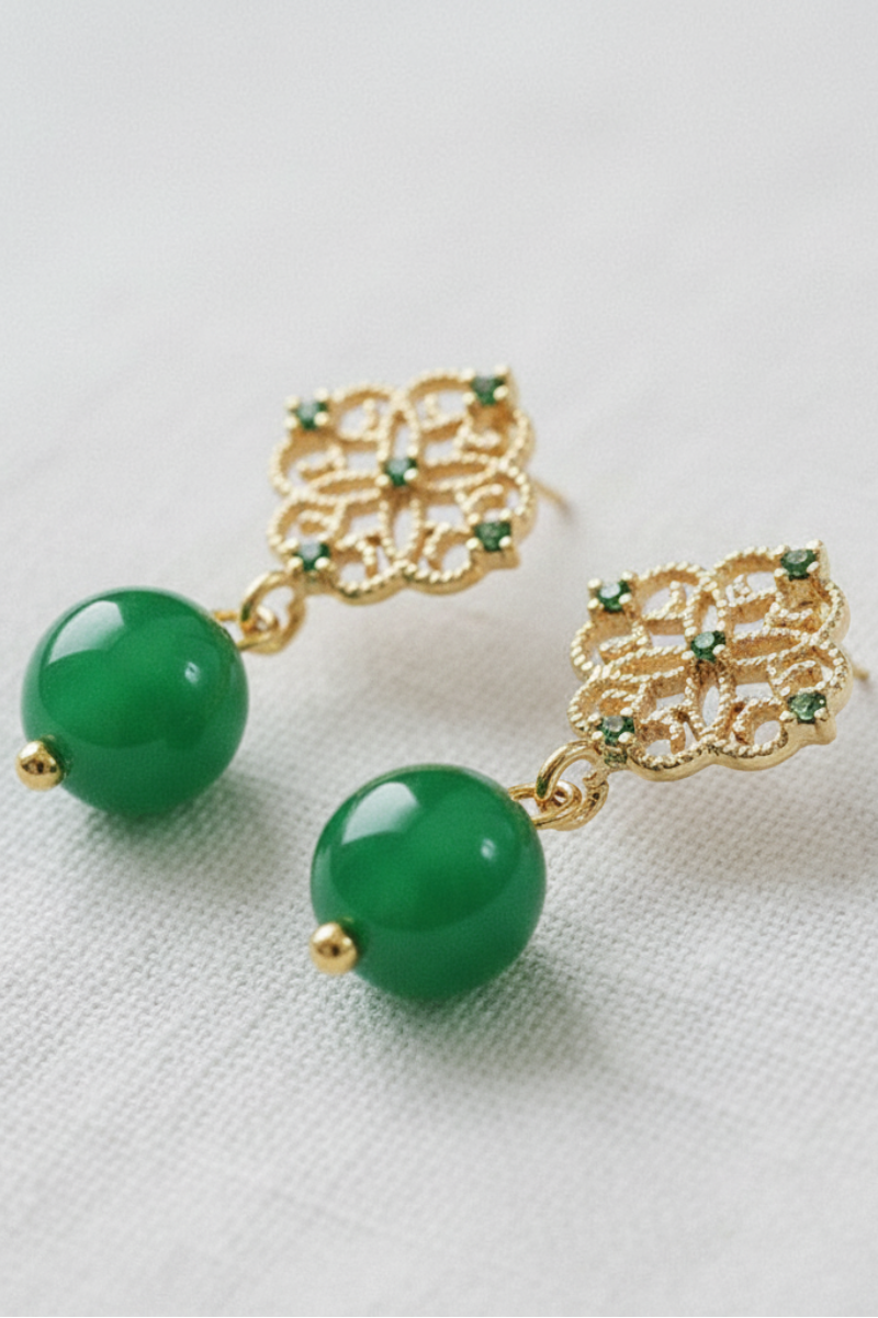 Green earrings with gold accents on a light gray background