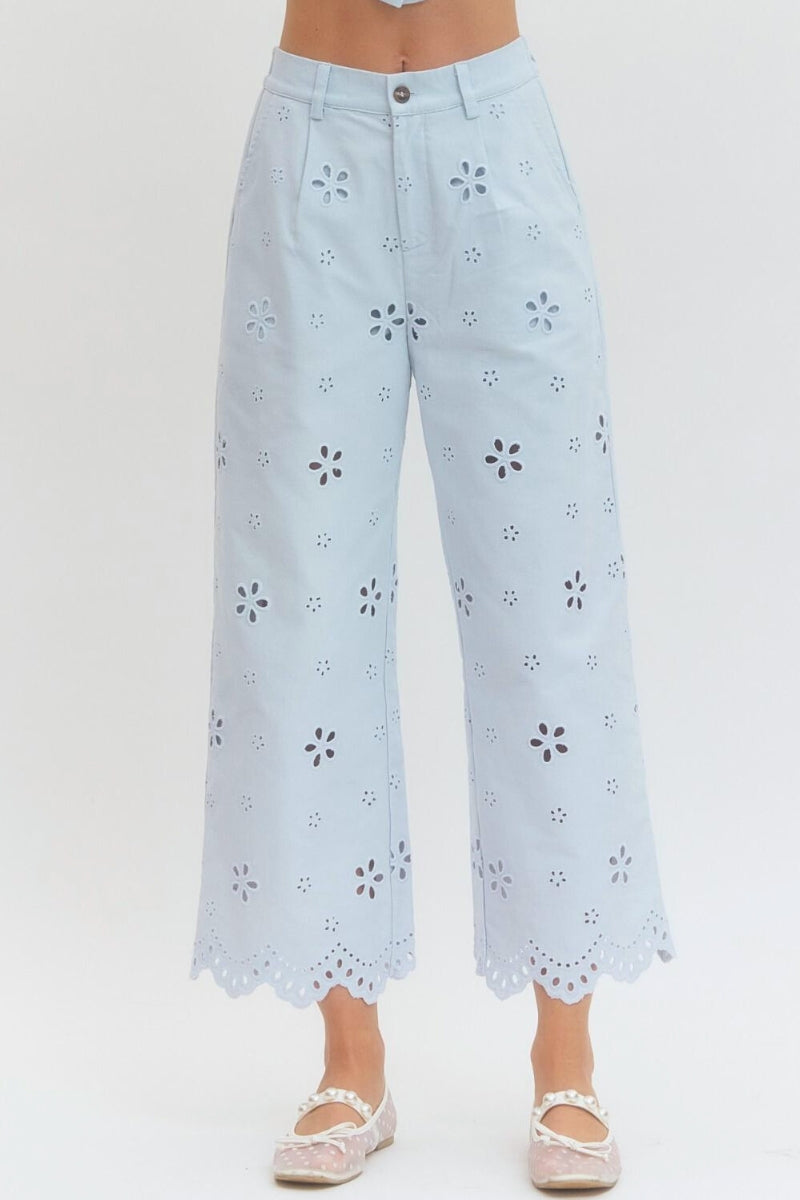 Light blue pants with floral cut-out pattern on a white background