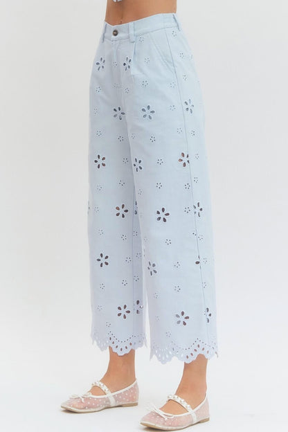 Light blue pants with floral cut-out pattern on a white background