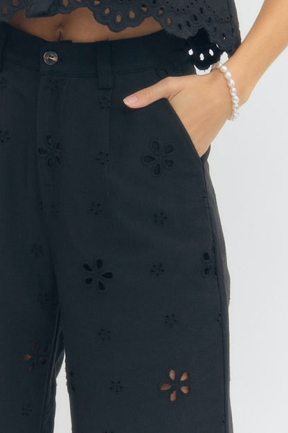 Black pants with floral cut-out details worn by a person.