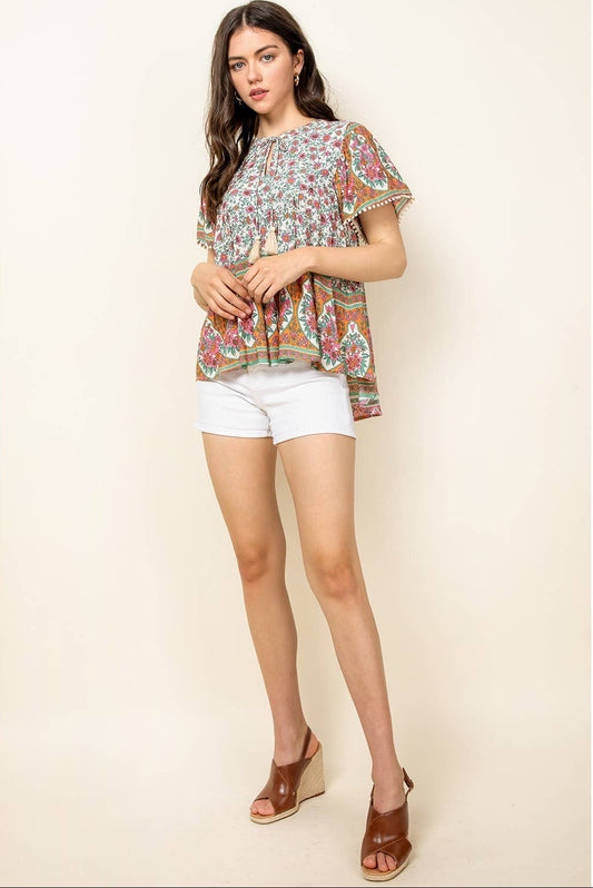 Woman wearing a floral blouse and white shorts on a beige background