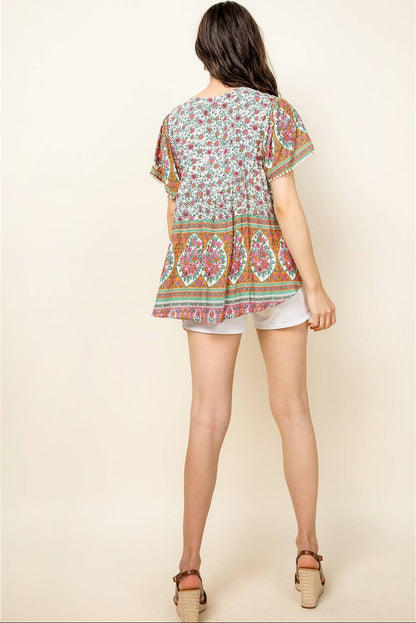 Woman wearing a colorful patterned top and white shorts on a beige background