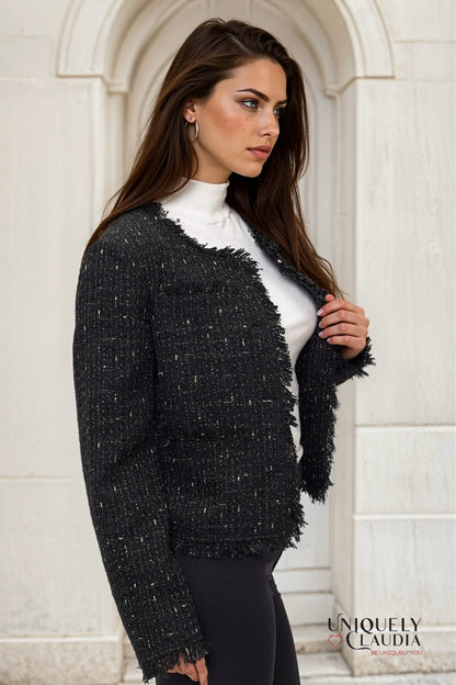 Woman wearing a black tweed jacket in front of a stone archway
