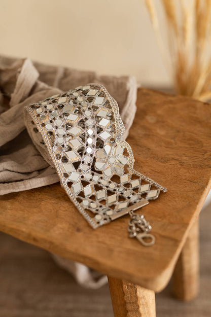 A close-up of a cream and beige wide decorative waistband covered in reflective mirrored tiles.