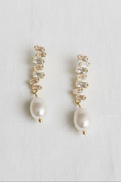 Pair of earrings with pearls and clear stones on a light gray background