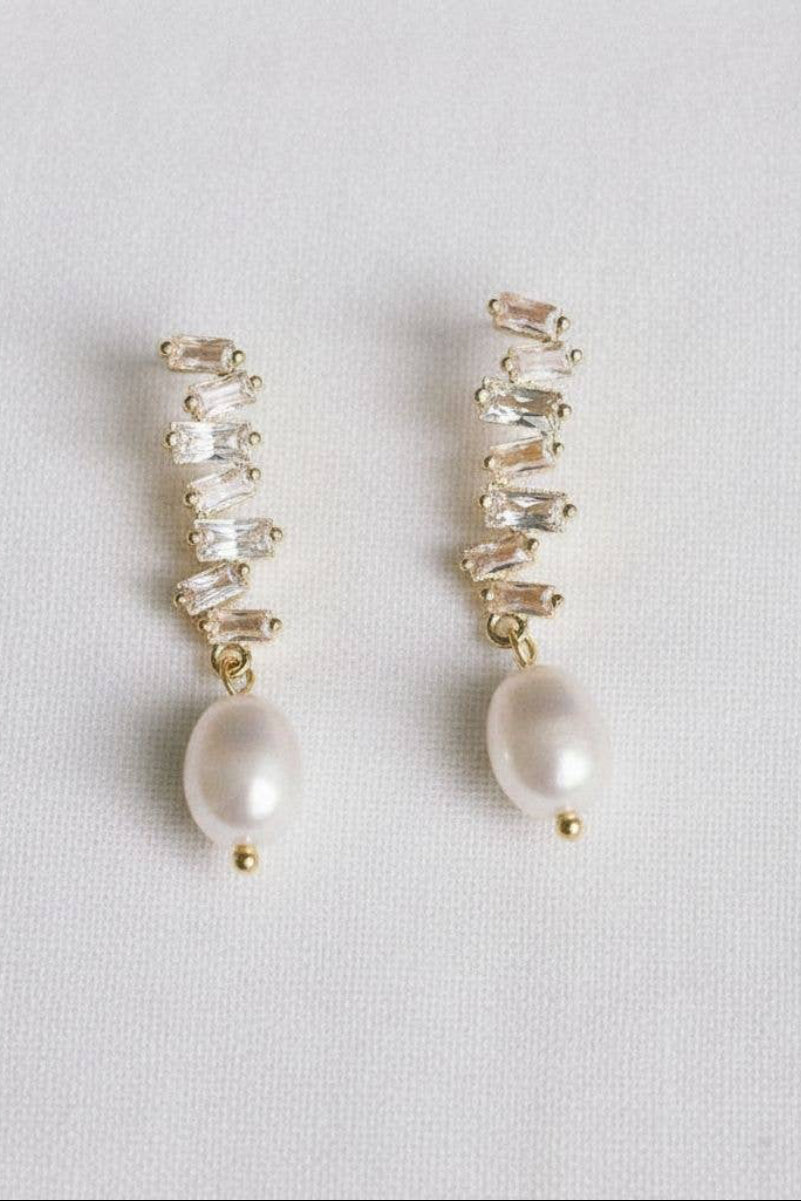 Pair of earrings with gemstones and pearls on a light gray background