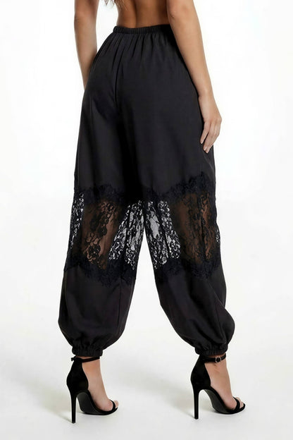 Black harem-style pants with sheer lace panels near the lower legs, shown on a model from the back against a plain white studio background.