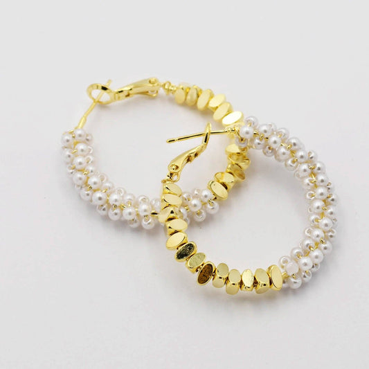Gold hoop earrings with pearl and bead detailing on a light gray background