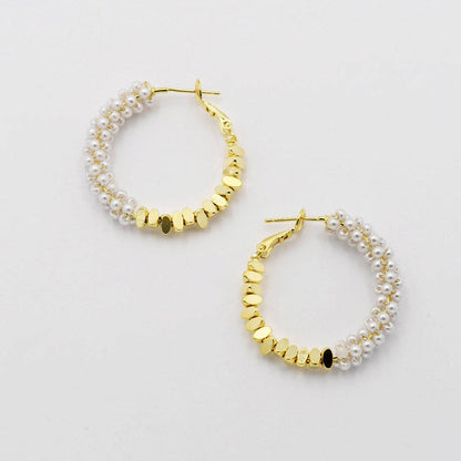 Gold hoop earrings with pearl accents on a light gray background