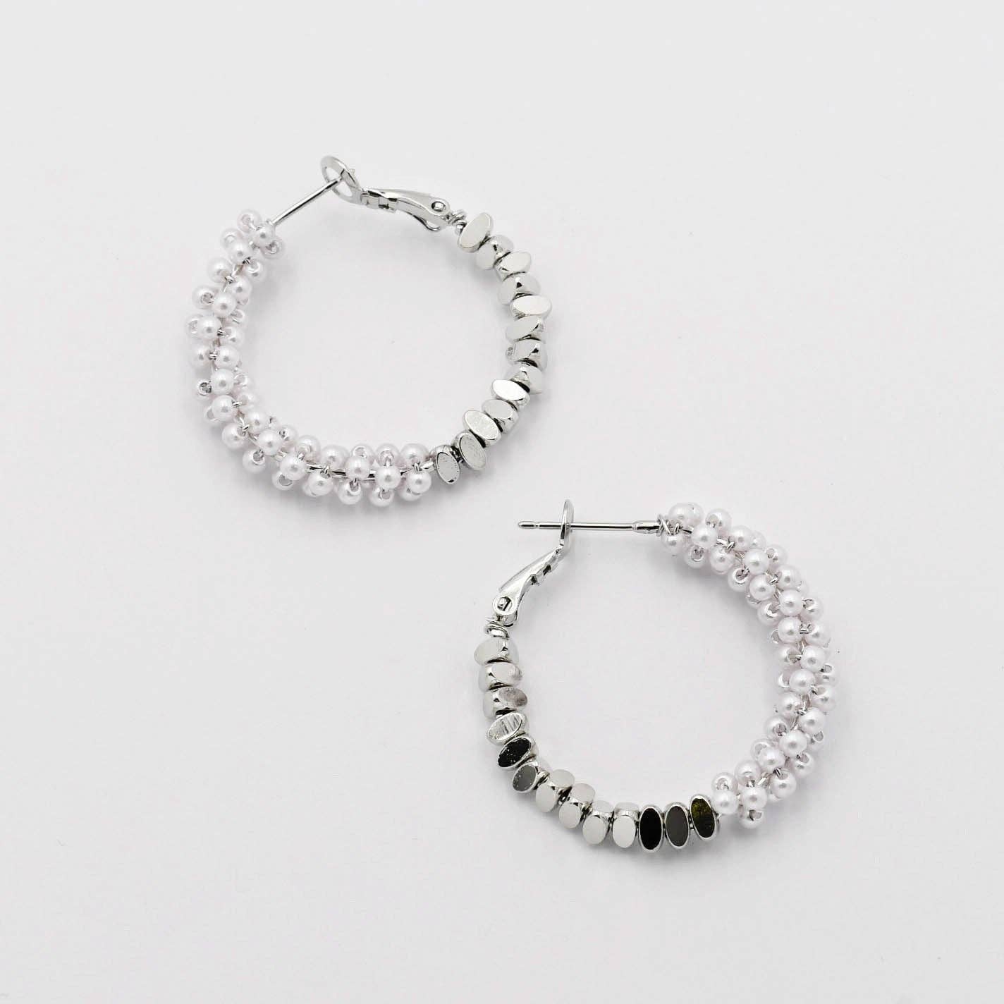 Silver hoop earrings with beaded design on a light gray background