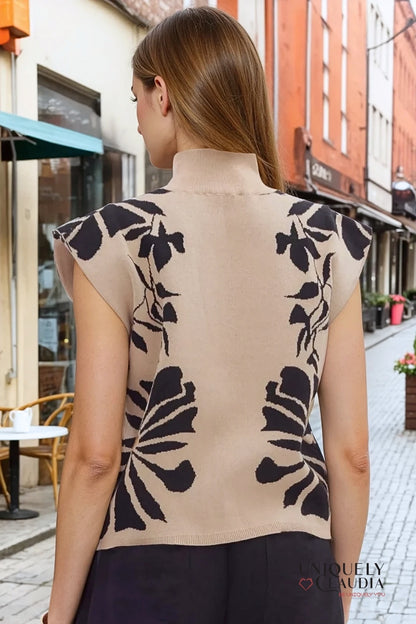 Woman wearing a beige sleeveless top with black floral patterns in an urban setting.