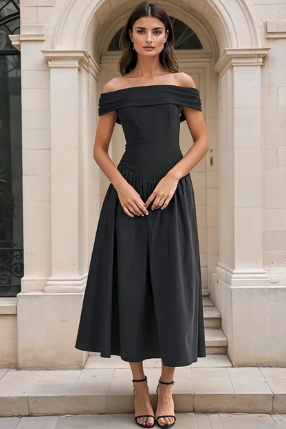 Woman wearing a black off-shoulder dress standing in front of a classical building.
