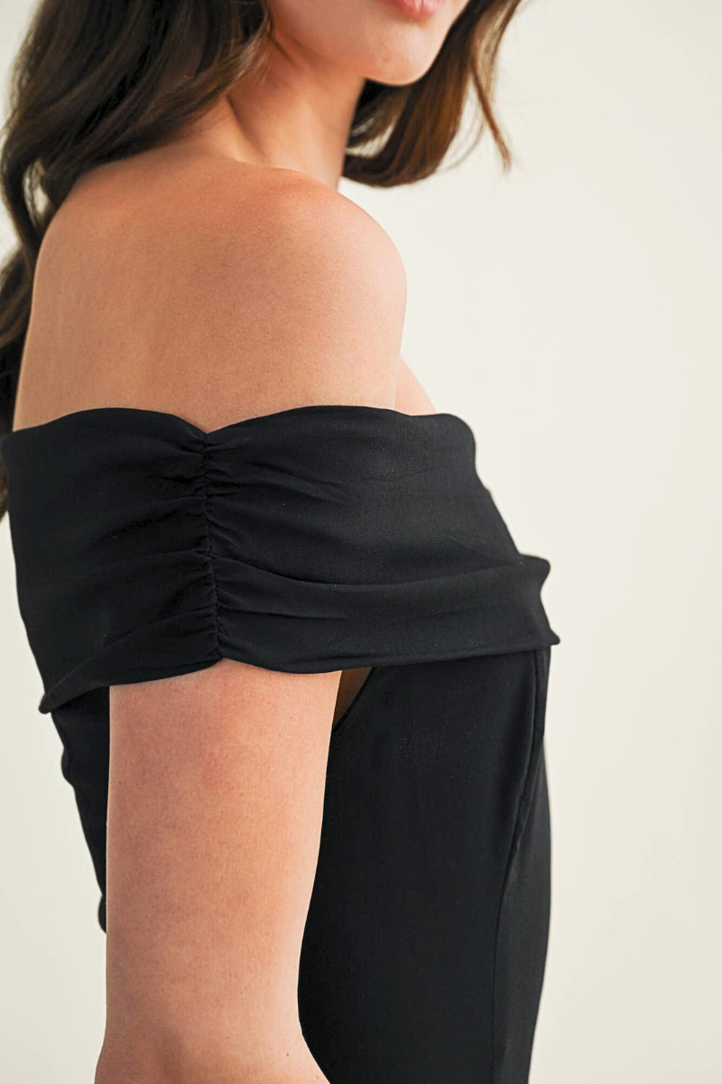 Black strapless top worn by a person on a plain background