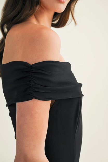 Black strapless top worn by a person on a plain background
