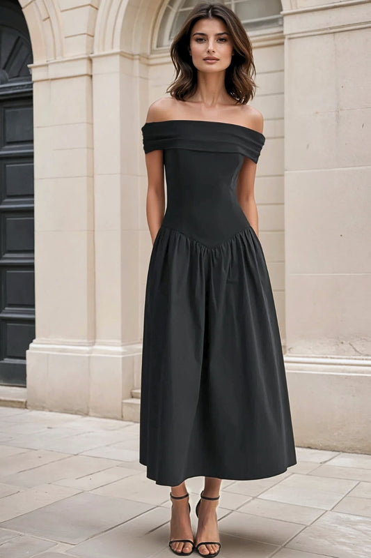 Woman wearing a black off-shoulder dress standing in front of a building.