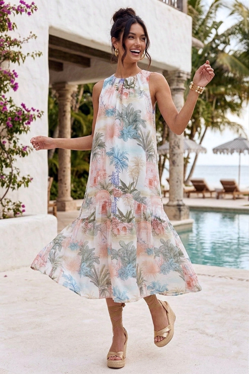 Woman in a floral dress standing by a poolside with a tropical setting.