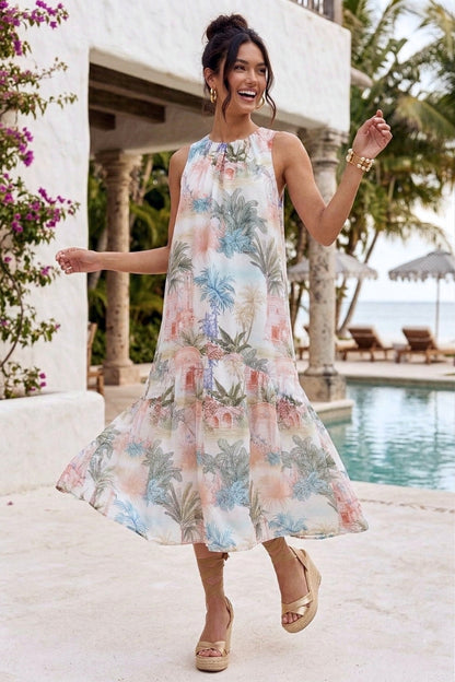 Woman in a floral dress standing by a poolside with a tropical setting.