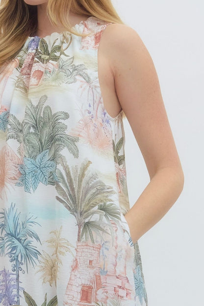 Person wearing a sleeveless dress with tropical palm tree and building print on a white background
