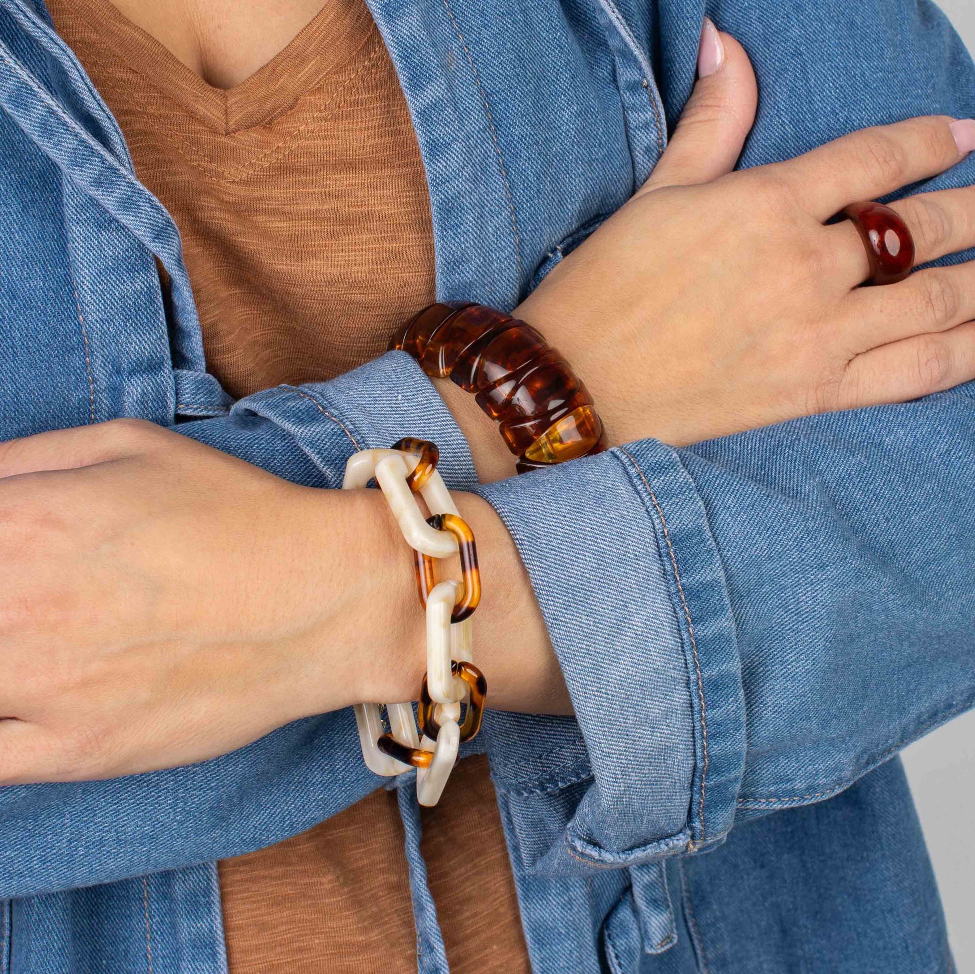 Person wearing a tortoiseshell bracelet on a plain background