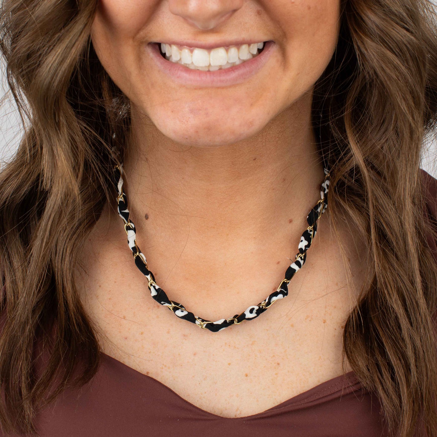 Woman wearing a black and white patterned necklace against a neutral background
