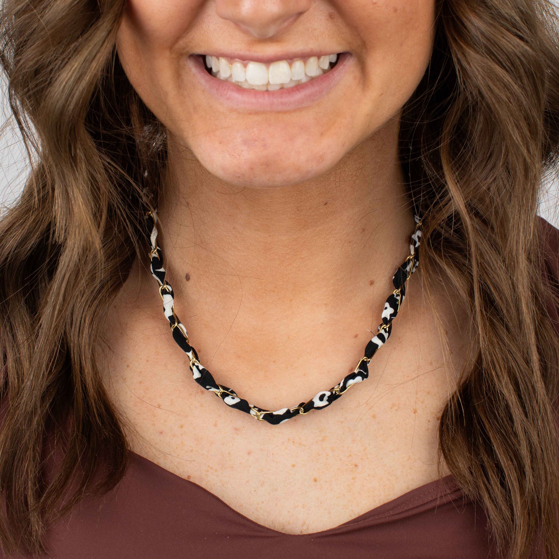 Woman wearing a black and white patterned necklace against a neutral background
