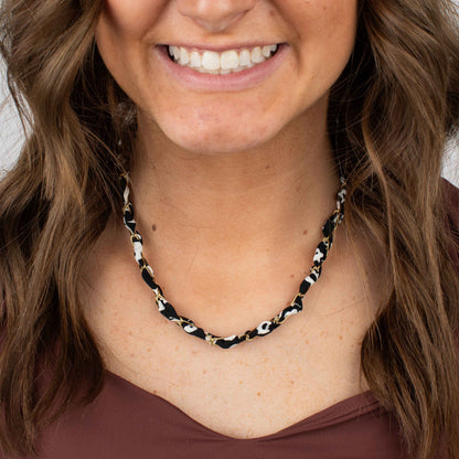 Woman wearing a black and white patterned necklace against a neutral background