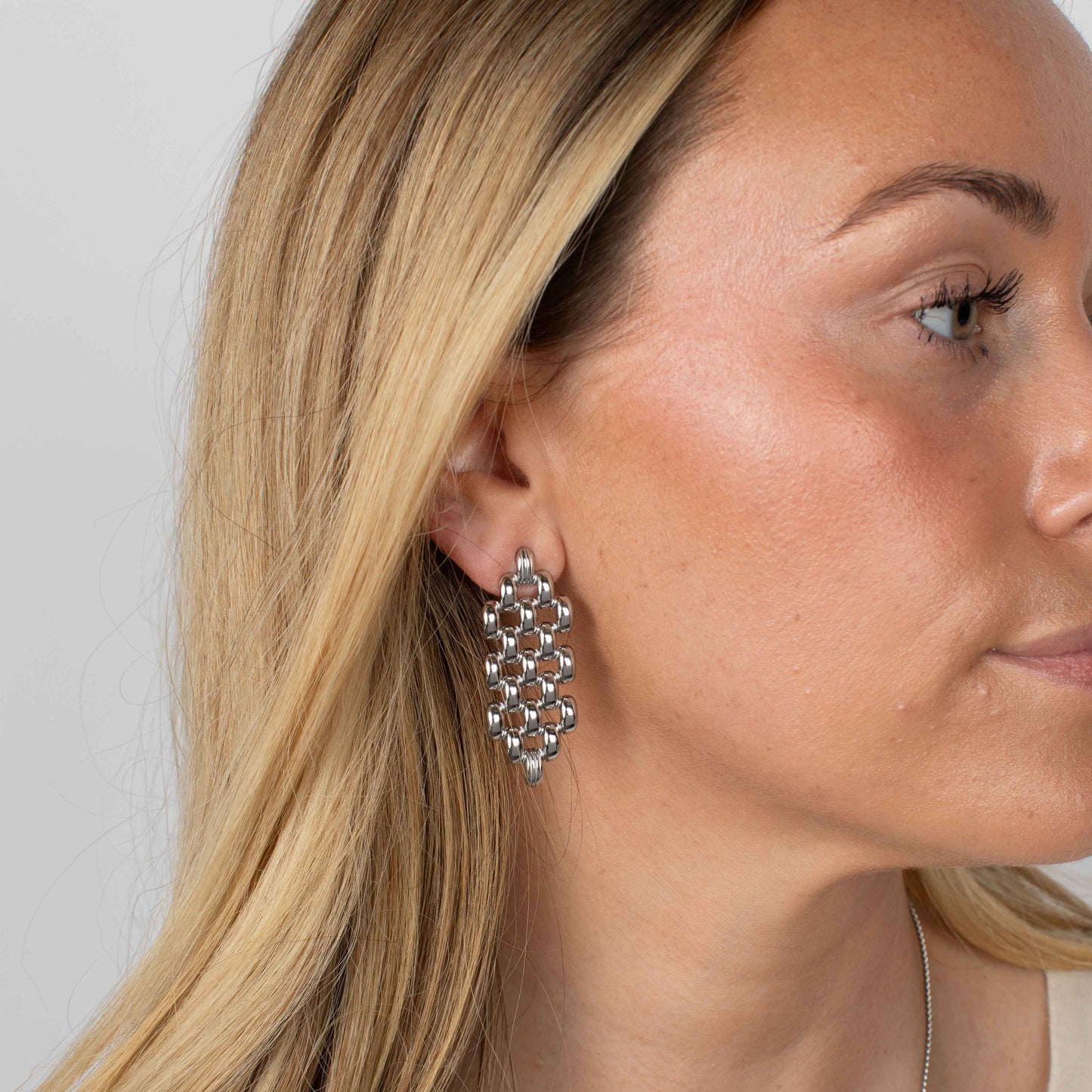 Close-up of a woman wearing a silver earring with a white background