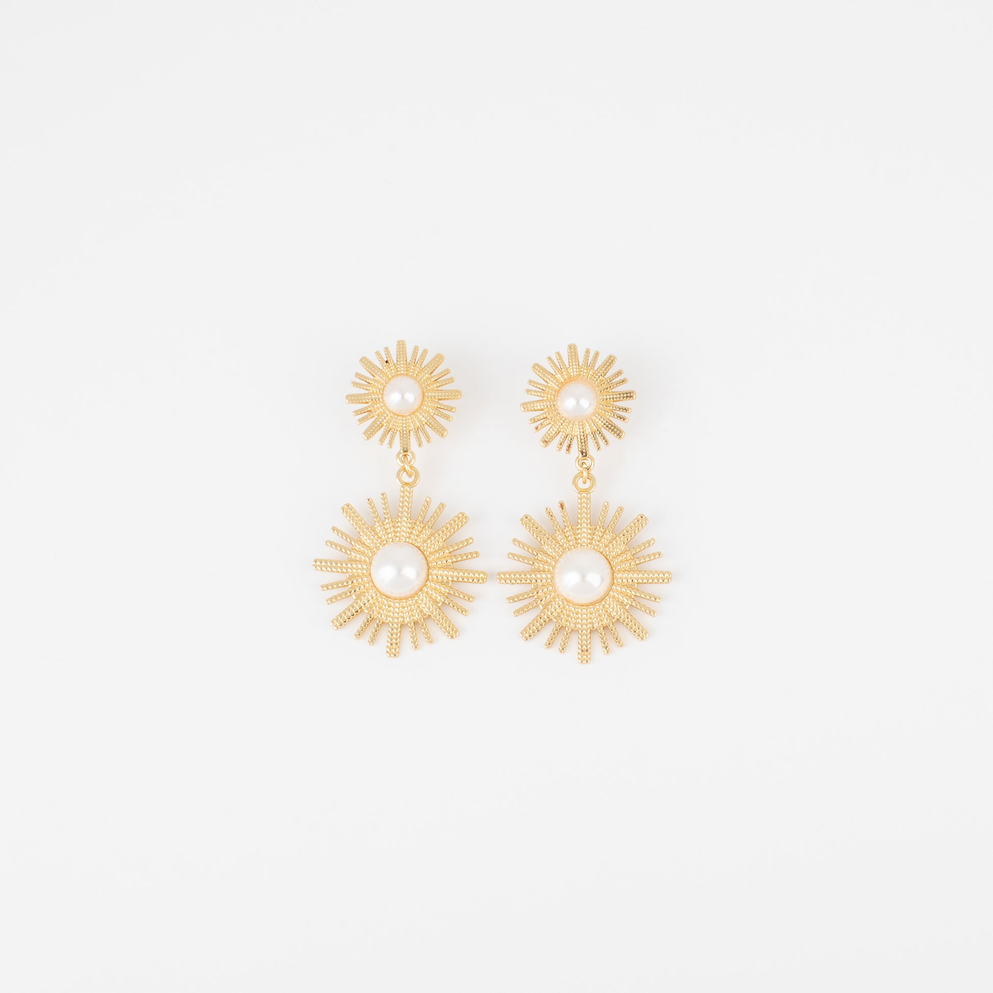 Gold sunburst earrings on a light gray background