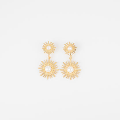 Gold sunburst earrings on a light gray background