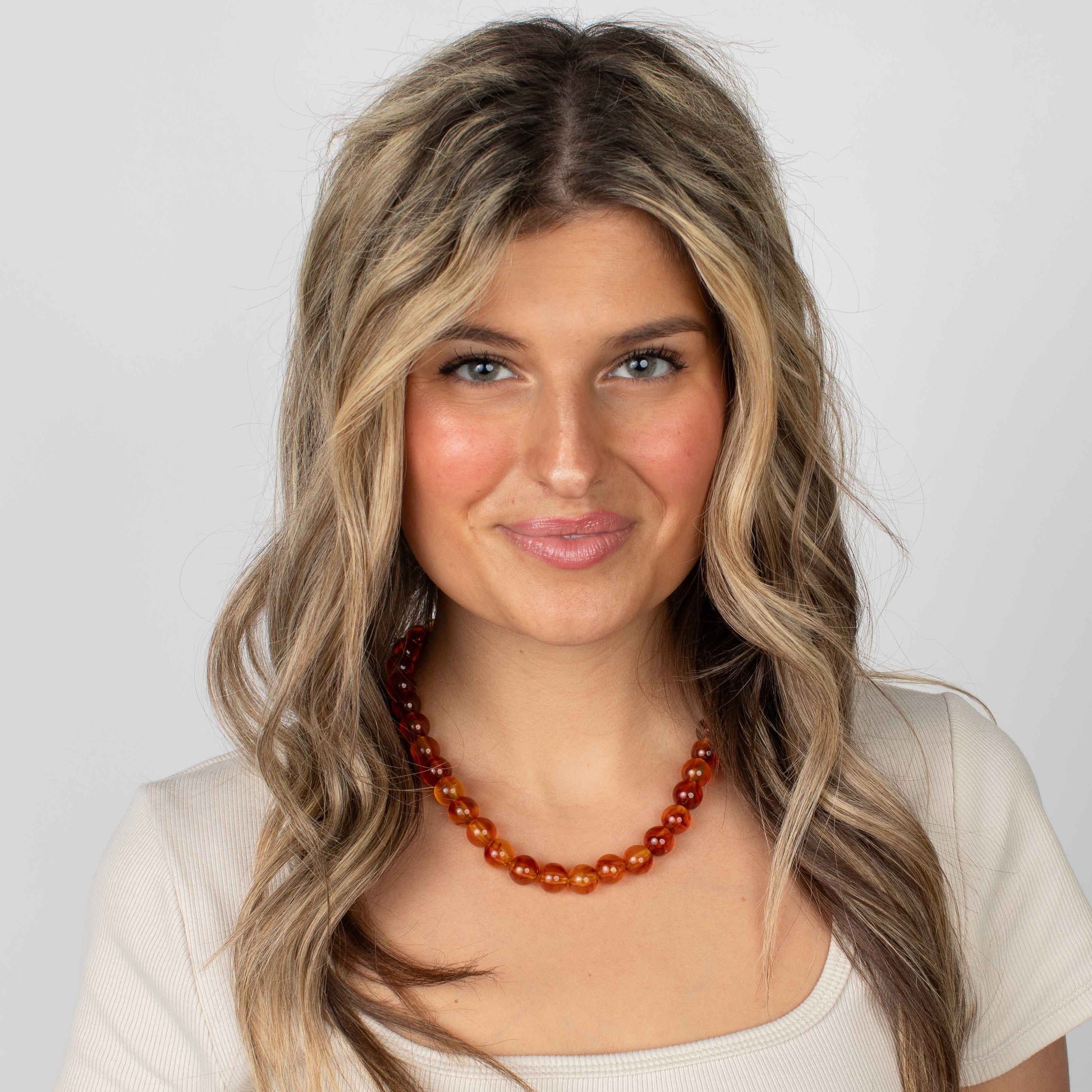 Woman wearing a necklace with a plain background