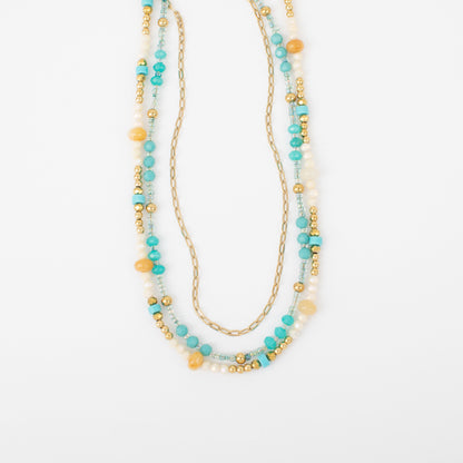 Multistrand beaded necklace with gold chain on a white background
