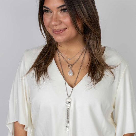 Woman wearing layered necklaces against a plain background