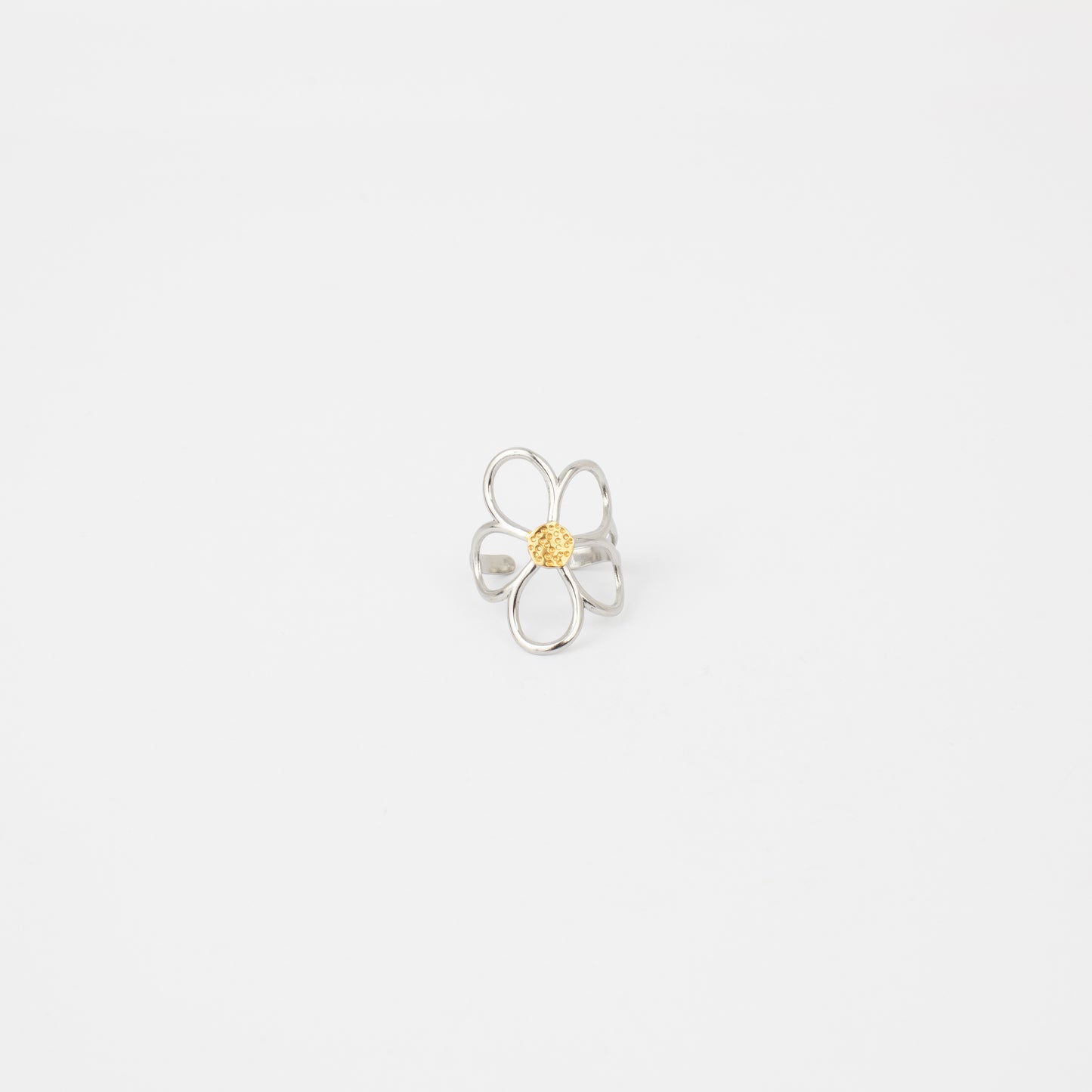 Silver flower-shaped ring with a yellow center on a light gray background