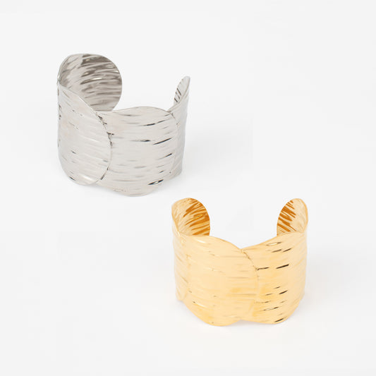 Two metallic cuff bracelets, one silver and one gold, on a white background.