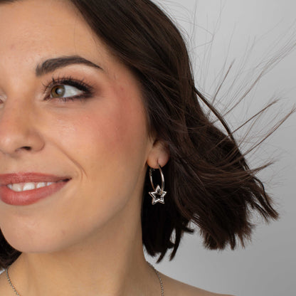 Close-up of a woman wearing star-shaped earrings with a neutral background