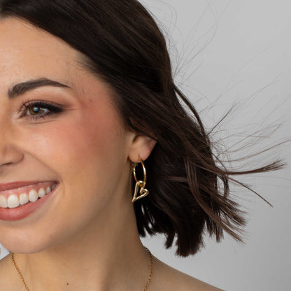 Close-up of a woman wearing a gold hoop earring with a neutral background