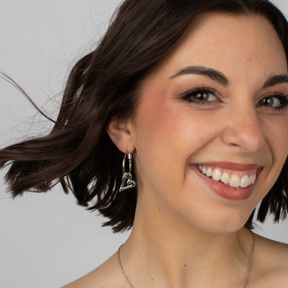 Close-up of a woman with dark hair and a smile, wearing a triangle-shaped earring.