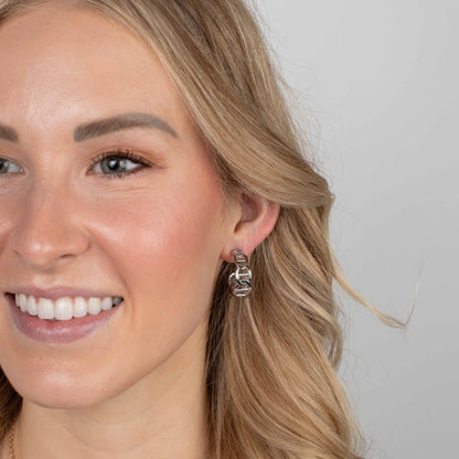 Close-up of a woman wearing silver earrings with a plain background