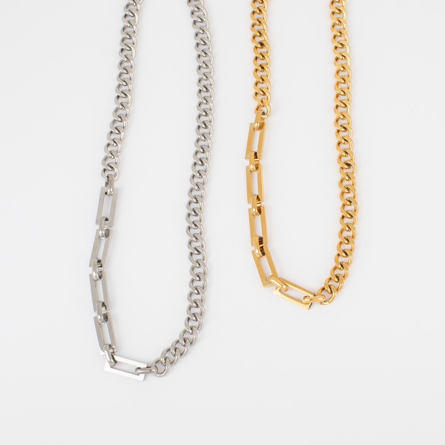 Two chain necklaces, one silver and one gold, on a white background