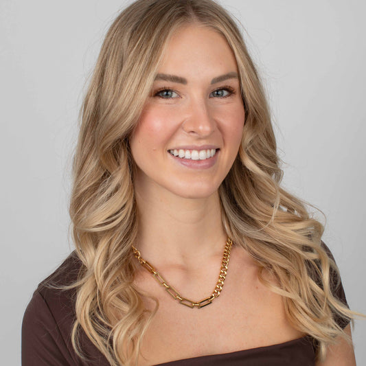 Woman wearing a gold necklace against a plain background