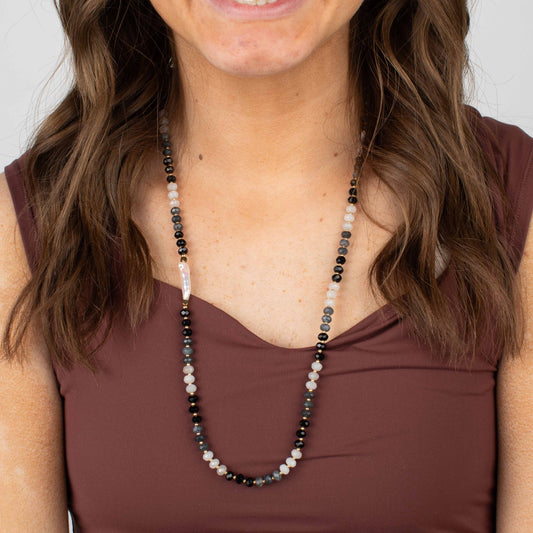 Woman wearing a beaded necklace with a plain background