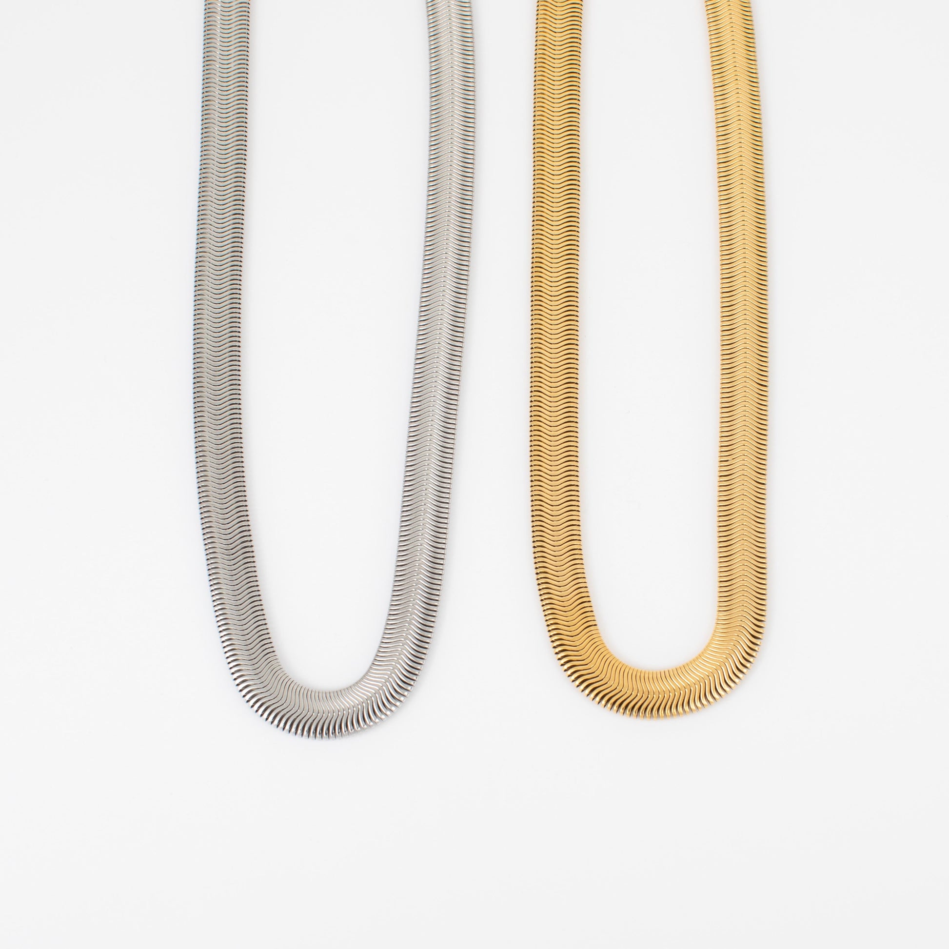 Two necklaces, one silver and one gold, on a white background