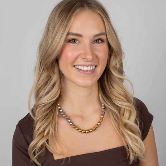 Woman wearing a beaded necklace with a plain background