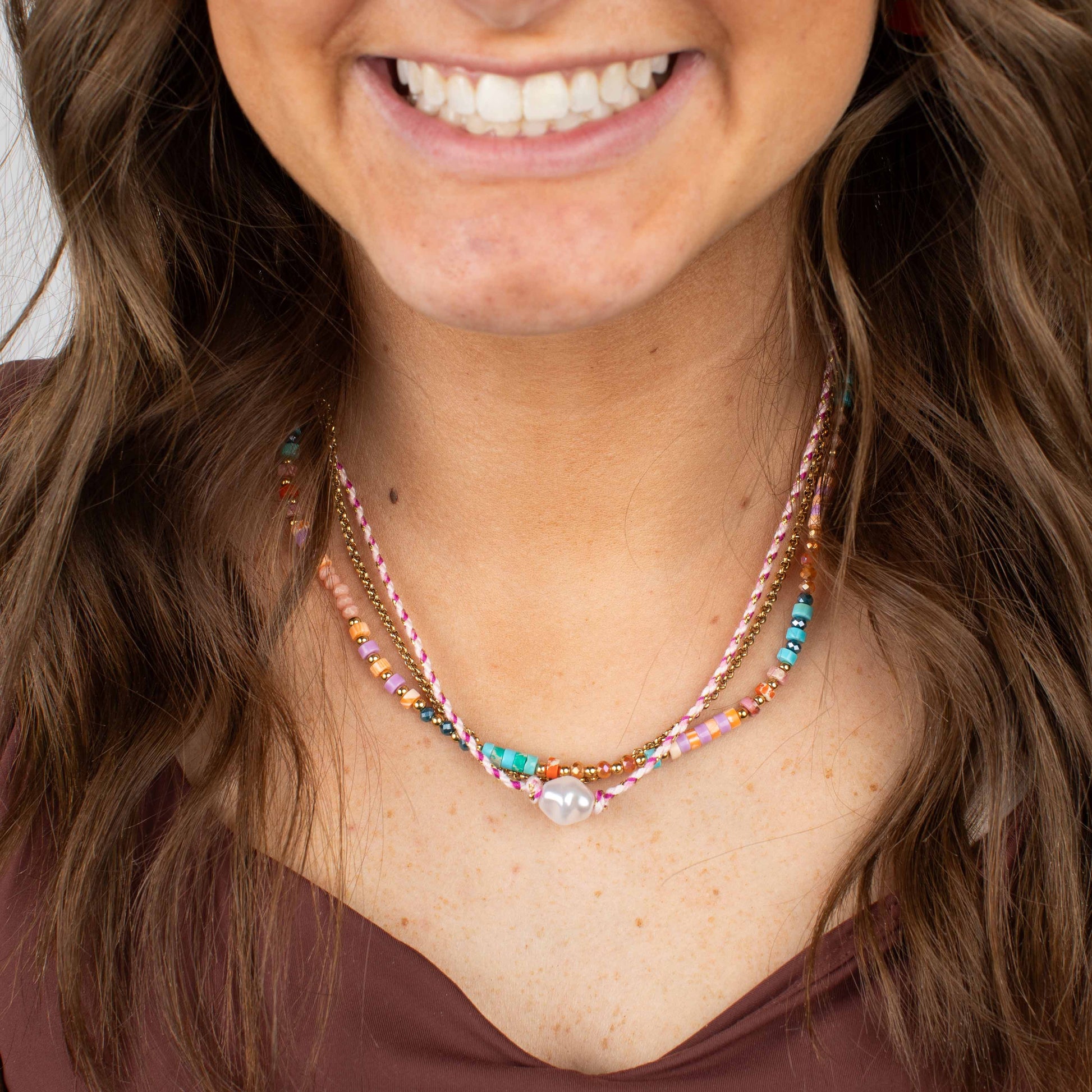 Close-up of a woman wearing a colorful beaded necklace with a blurred background