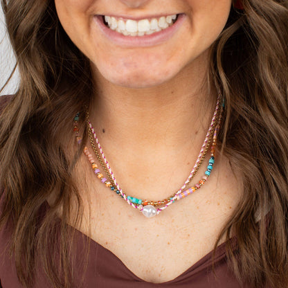 Close-up of a woman wearing a colorful beaded necklace with a blurred background