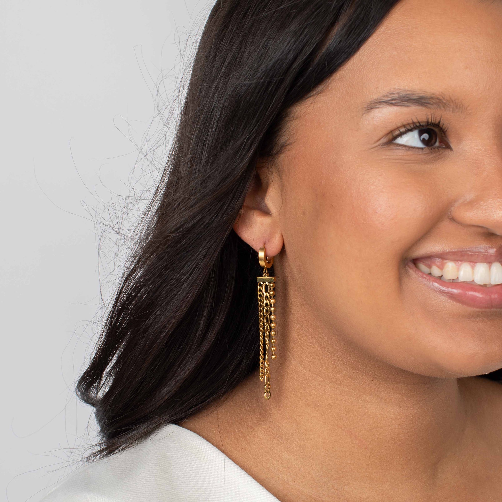 Woman wearing gold earrings with a neutral background