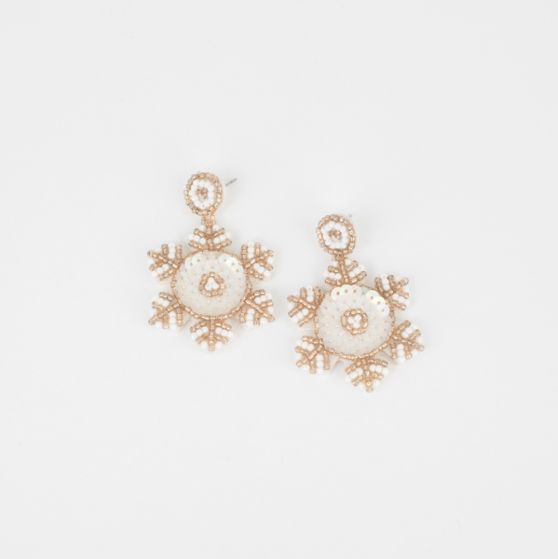 Snowflake-shaped earrings with gold and pearl details on a light gray background