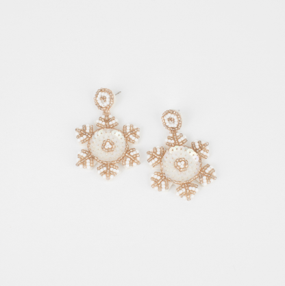 Snowflake-shaped earrings with gold and pearl details on a light gray background
