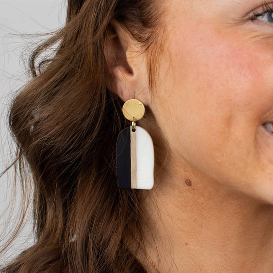 Close-up of a woman wearing a gold, black, and white earring.