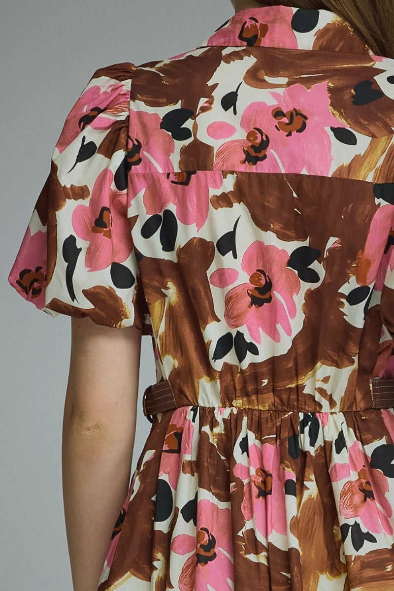 Close-up back view of a person wearing a short-sleeve dress with a brown, pink, and cream floral painterly print and a gathered waist.